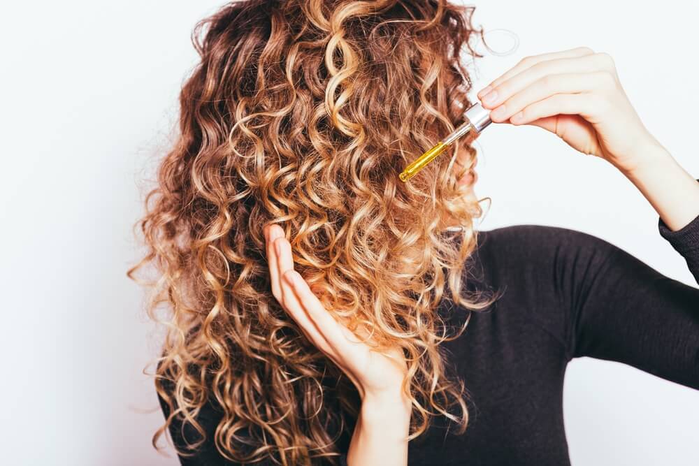 Woman applying HerStyler hair serum