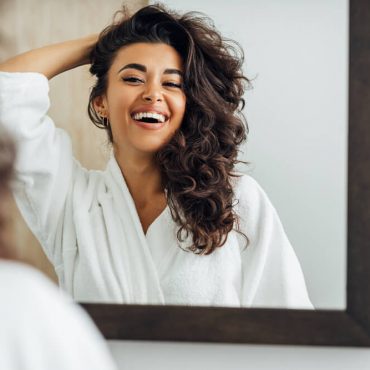 Woman looking in mirror before she styles thick hair