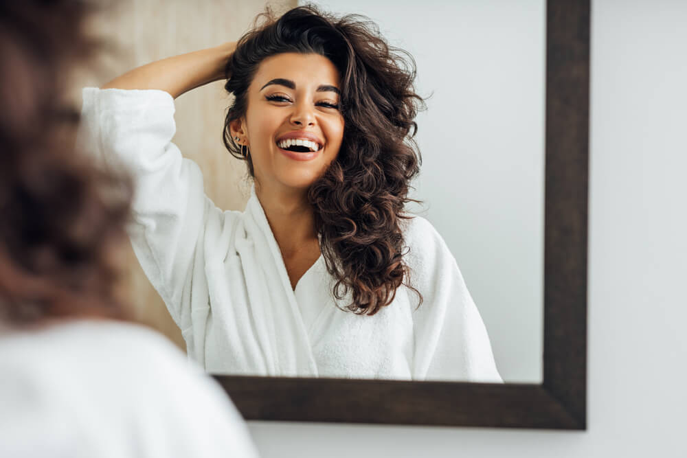 Woman looking in mirror before she styles thick hair