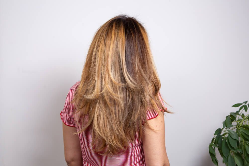 Woman styling thick hair with layers