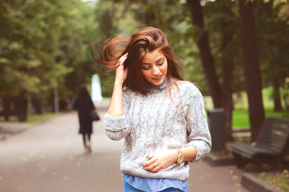 Young woman touching her hair outdoors on a windy fall day